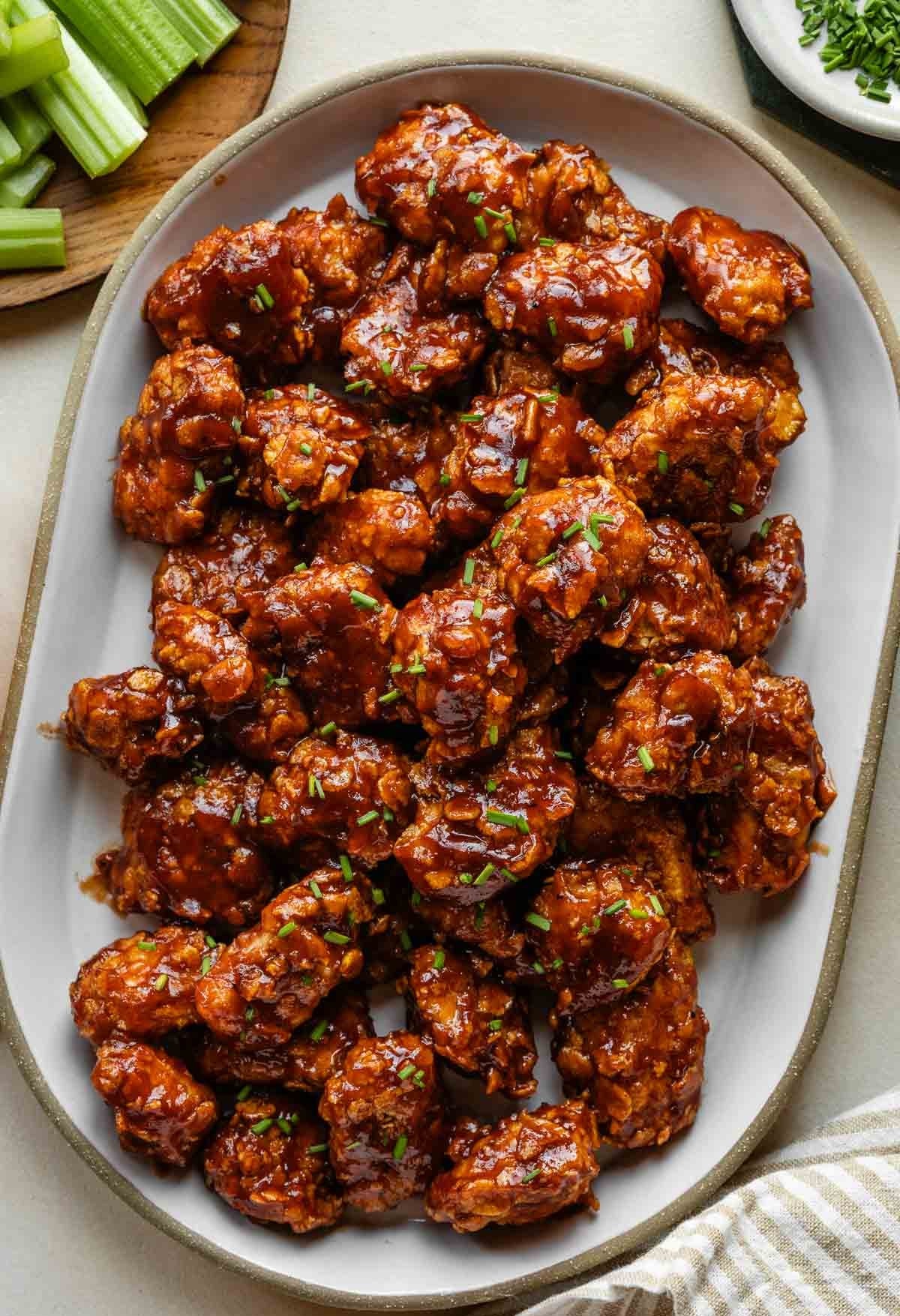 Crispy Air Fryer Honey BBQ Chicken Bites on a white platter, garnished with green onions.