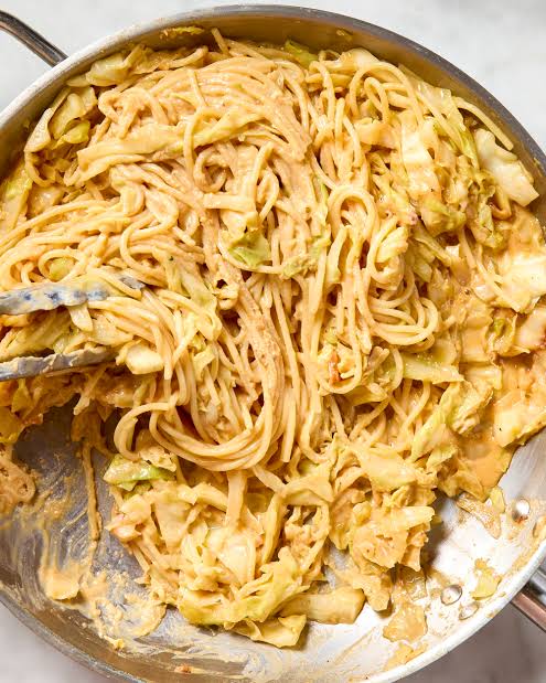 A stainless steel pan filled with creamy cabbage carbonara pasta, mixed with crisp roasted cabbage ribbons and a velvety parmesan sauce