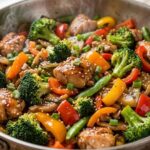 A close-up shot of homemade easy chicken stir fry with colorful vegetables like broccoli and bell peppers in a skillet.