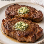 Air fryer steak topped with melted garlic herb butter on a plate